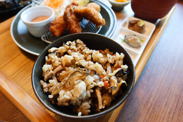 Japanese steam rice with oyster in a black bowl in the set of wooden tray