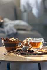 Tea ceremony, glass cup of black tea and teapot on blurred home background.