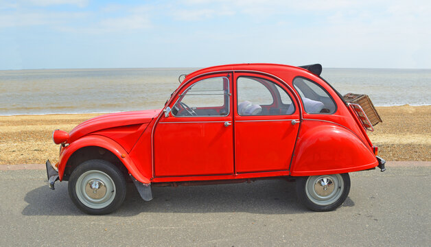 Classic Red Citroen 2CV  deux chevaux parked on seafront promenade.