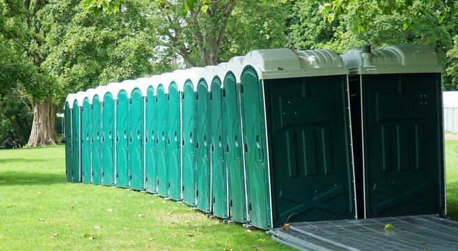 Row of Portaloo in park on grass sunny day