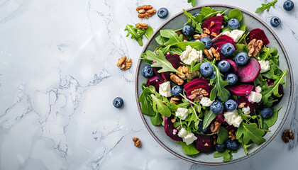 Delicious salad with sweet beets, blueberries, feta cheese, arugula and walnuts, with empty copy Space, light marble table background, top view