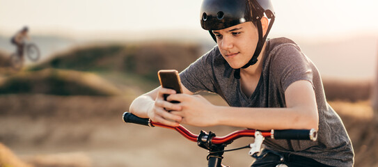 Teenager with a bicycle helmet,using a mobile phone,messaging