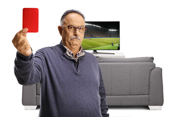Serious mature man showing a red card in front of a tv screen