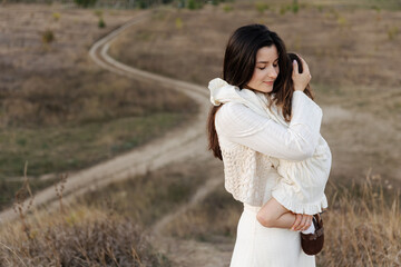 mother holds her little cute daughter in her arms and hugs her tightly