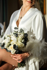 The bride in a white wedding dress holds a wedding bouquet. The bouquet consists of white and pink...