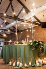 The newlyweds' presidium in the restaurant's banquet hall is decorated with candles and green plants.wedding day
