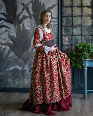 An aristocratic girl in a vintage dress walks through the hall