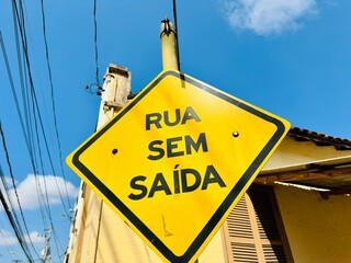 Placa de sinalização num poste  rua sem saida na cor amarela e bordas pretas.