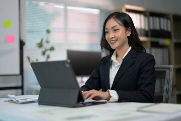 Professional Businesswoman Working on Tablet in Modern Office Setting with Natural Light