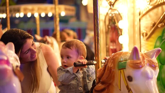 M&atilde;e e filho brincando no carrossel em um parque de divers&atilde;o 