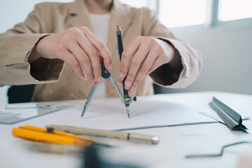 In her office, the professional woman architect meticulously uses a compass in hand to refine the blueprint, embodying precision and expertise as a designer on the project.