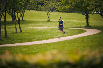 Nature, fitness and man in park for running challenge, wellness and healthy outdoor exercise. Training, cardio and runner on path in morning with commitment, progress and athlete in muscle workout.