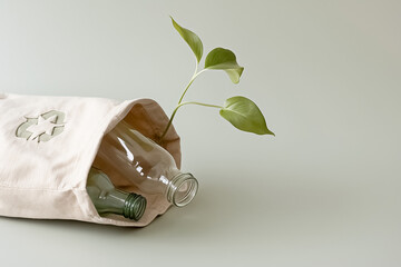 craft bag with a recycling icon. Protruding from the bag's opening is an empty, plastic bottle and a glass bottle