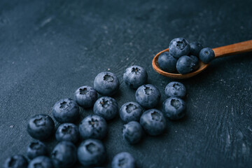 Wooden spoon and a pile of fresh blueberries, background