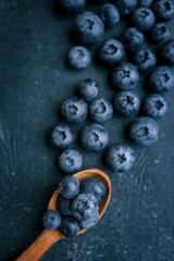 Wooden spoon and a pile of fresh blueberries, background
