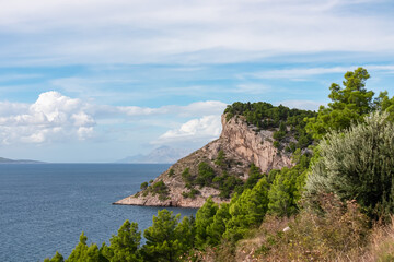 Fototapeta premium Breathtaking coastal vista featuring a rugged cliff rising dramatically from crystalline blue sea of Adriatic sea along Makarska Riviera coastline Split-Dalmatia, Croatia, Europe. Travel destination
