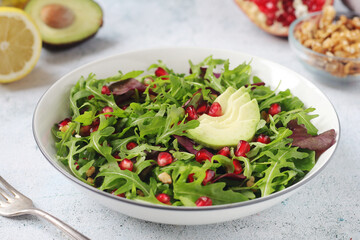 A plate with green rocket salad with pomegranate and avocado