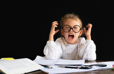 A little girl with glasses gets angry when she does her homework from school. Learning Difficulties for Young Children