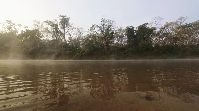 Time lapse fishermen fishing with net ride on boat in Chitwan national park. Jungles buffer zone on misty morning