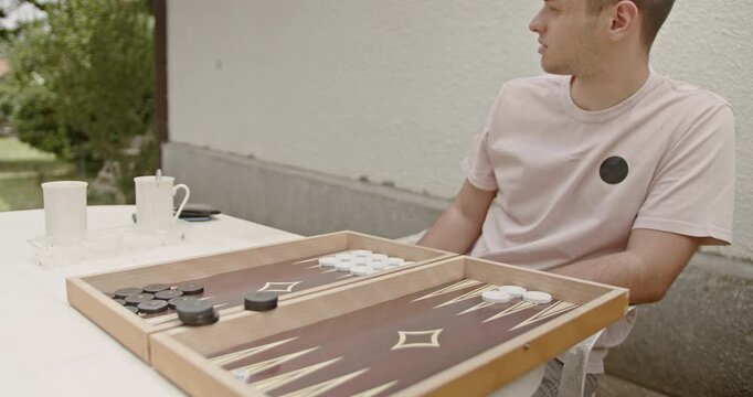 Young friends playing a game of backgammon outdoors. Capturing a casual and relaxing moment of leisure and social interaction.