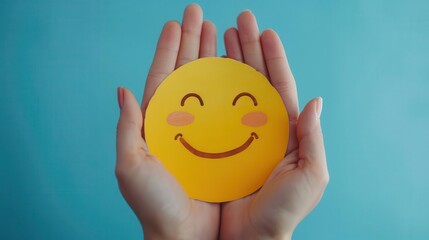 Closeup of hands holding a yellow smiley face on a blue background.