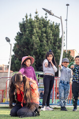 vertical latina girl gets teased and laughed at by her schoolmates in a park in bolivia - abuse concept