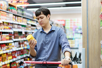 Asian man looking for foods and beverages in supermarket.