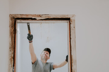 A man working with a crowbar in a doorway.