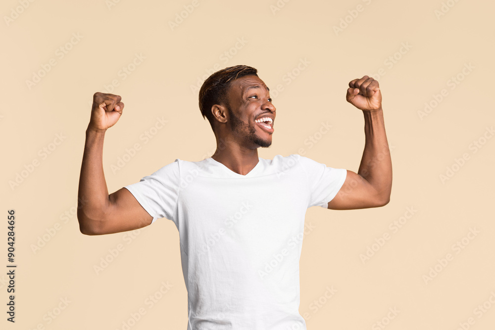 Wall mural Yes. Excited Afro Guy Rejoicing Success Shouting And Shaking Fists Standing On Yellow Background. Studio Shot