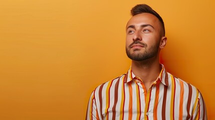 Obraz premium an image of a confident guy in a striped shirt against an orange background, with clear space available for text integration