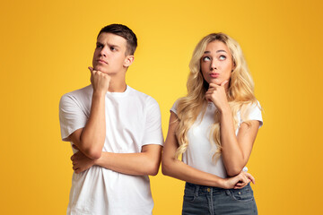 Thinking about solution. Portrait of pensive millennial couple couple on yellow studio background with free space