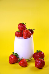Strawberry milkshake. Glass of milk with fresh strawberries on a yellow background. Berries in a glass.