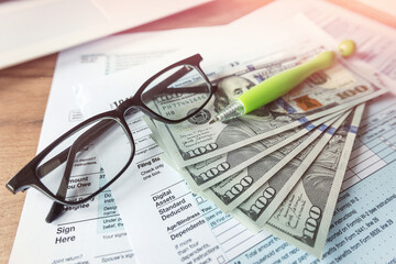 accounting paperwork individual tax form 1040 glasses dollar and pen on desk