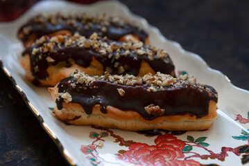 Classic chocolate eclair with custard cream and chopped walnuts on top