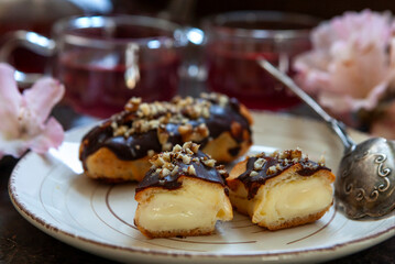 Classic chocolate eclair with custard cream and chopped walnuts on top