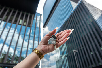 Real estate agent with house key against  background of skyscrapers in city