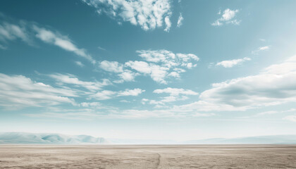 A vast, empty desert landscape under a bright blue, partly cloudy sky, with distant rolling hills and a pathway stretching through the barren sand.