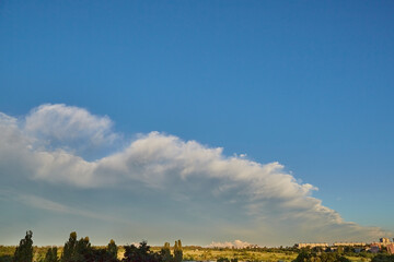 Obraz premium A ridge of white clouds on the horizon over a field and a grain elevator