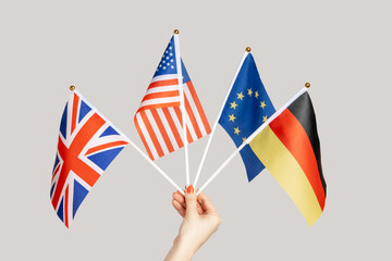 Closeup of woman hand showing Europe, British, american, German flags, countries friendship. Indoor studio shot isolated on gray background.