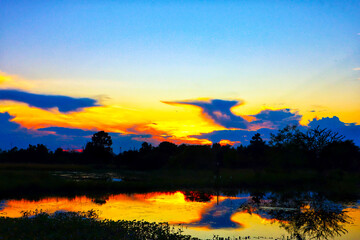 The atmosphere of the evening sunset shining through the clouds and the river reflecting beautifully and naturally, Lamphun Province, Southeast Asia, Northern Thailand