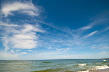 Empty, sandy beach and sea waves by sunny day