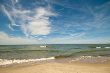 Empty, sandy beach and sea waves by sunny day