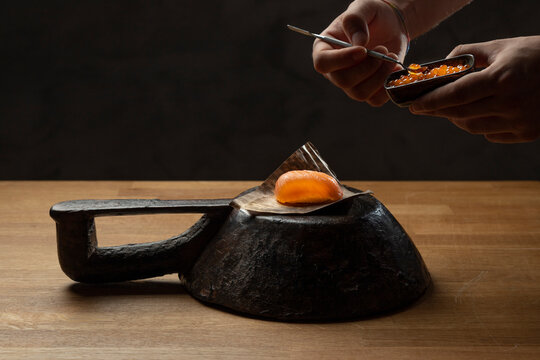 Hands decorating exquisite sushi on a traditional iron plate