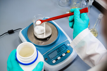 A woman chemist measures powder samples with laboratory balances