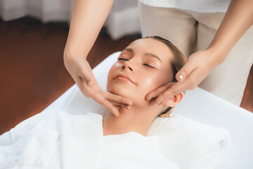 Caucasian woman enjoying relaxing anti-stress head massage and pampering facial beauty skin recreation leisure in dayspa modern light ambient at luxury resort or hotel spa salon. Quiescent