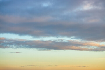 A beautiful sky tinted by the sun leaving vibrant shades of gold, pink, blue and multicolored. Clouds in the twilight evening and morning sky. Cloudy sky background in the evening and during the day.