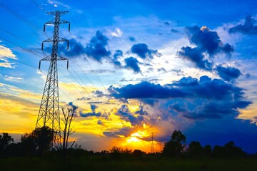 Beautiful colorful sunset sky background with blue tones shining through electric poles.