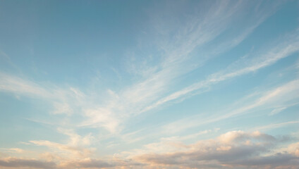 Obraz premium A serene sky featuring a soft blue background with wispy, white clouds gently streaked across, creating a peaceful and expansive atmosphere.