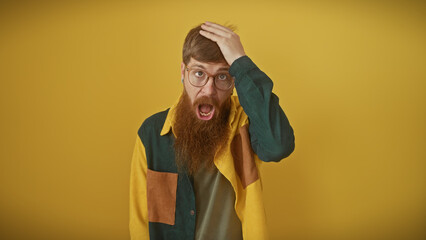 A shocked redhead bearded man in a colorful shirt expressing surprise against a yellow background.