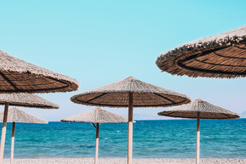 Calm relaxing travel background. Many palm beach umbrellas on sea coast. Copy space for your text. Luxury holiday vacation on the ocean or sea. Natural sunshade. Rhodes, Greece.
